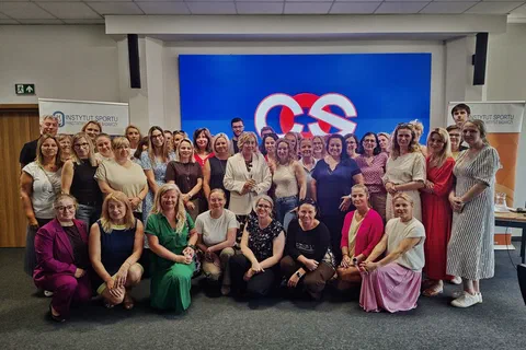 Grupowe zdjęcie uczestników szkolenia w sali konferencyjnej między banerami Instytutu Sportu – PIB i Akademii Zarządzania Sportem.