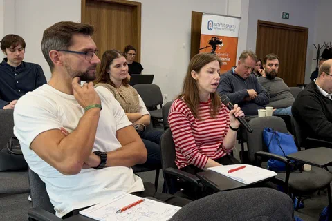 Uczestniczka siedząca na widowni i zabierająca głos przez mikrofon podczas dyskusji.