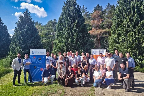 Grupowe zdjęcie uczestników szkolenia w plenerze na tle drzew i roll-upów.