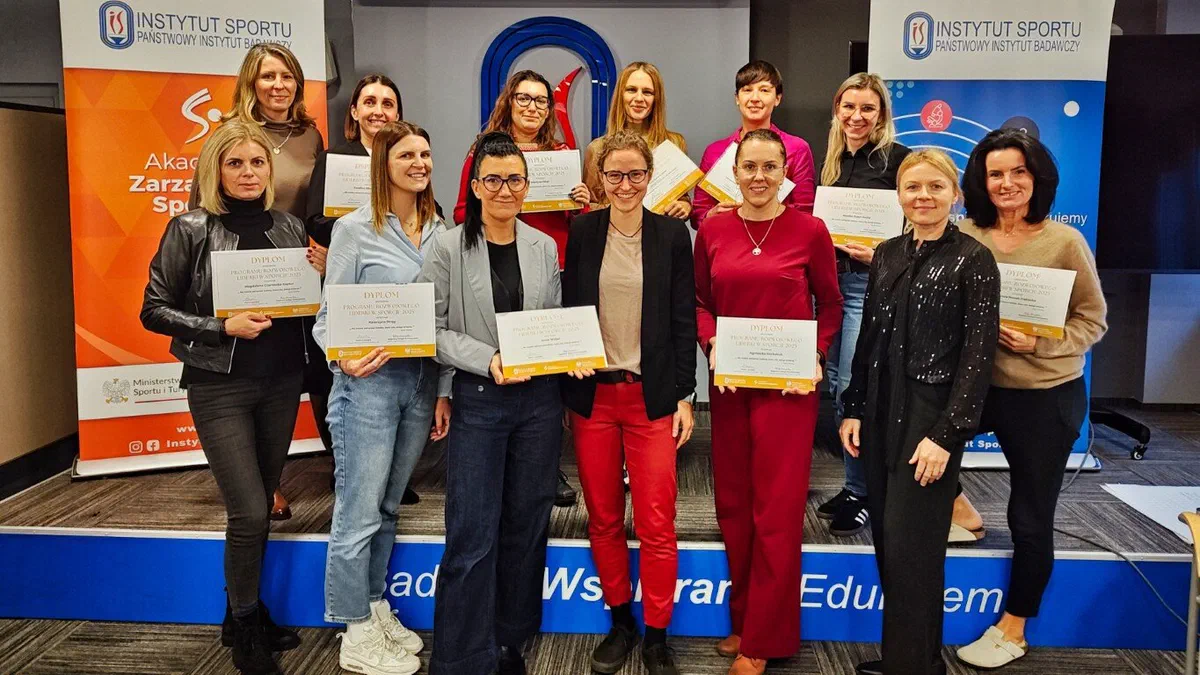 Grupowe zdjęcie uczestniczek trzymających certyfikaty ukończenia cyklu szkoleń „Liderki w sporcie 2025” na tle ścianki Instytutu Sportu – PIB.