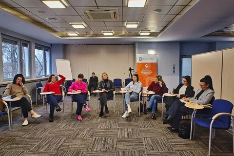 Uczestniczki warsztatów siedzące w półkolu i notujące na kartach ćwiczeniowych.