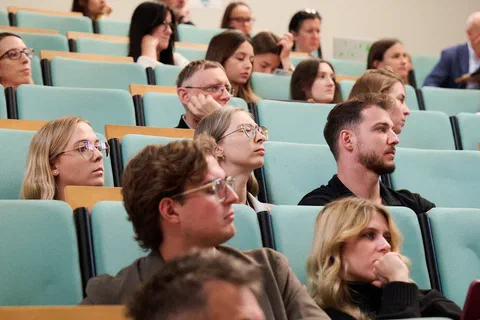 Słuchacze siedzący w rzędach amfiteatralnej auli wykładowej podczas konferencji.
