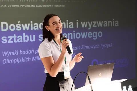 Prelegentka w białej koszulce przemawiająca na tle slajdu o doświadczeniach i wyzwaniach sztabu szkoleniowego.