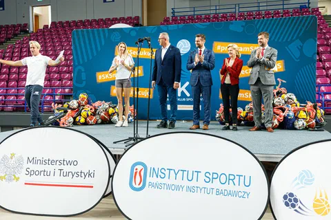 Goście i sportowcy klaszczący na scenie za bandami z logotypami Ministerstwa Sportu i Turystyki oraz Instytutu Sportu – PIB.