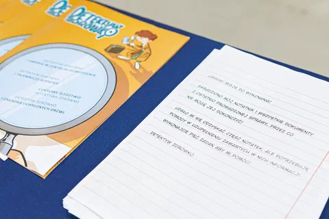 Zbliżenie na teczkę i kartę zadań edukacyjnych „Detektyw Zdrówko” leżące na stole.