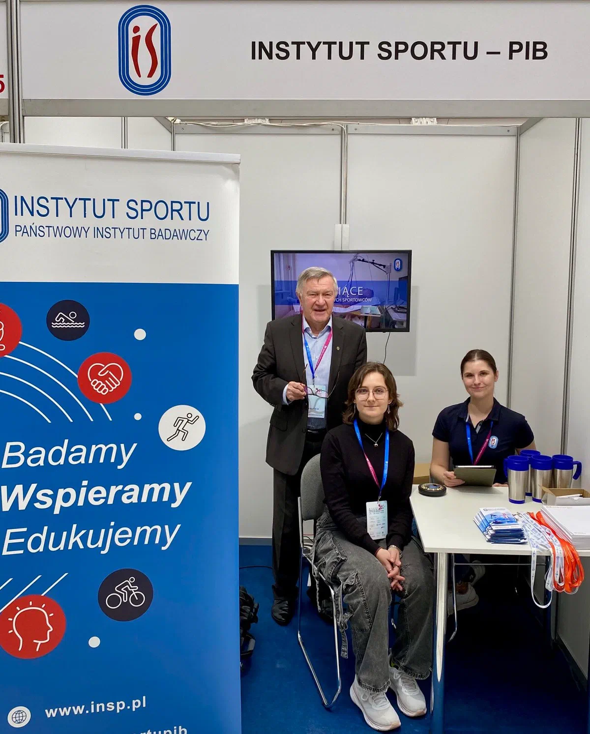 Trzyosobowy zespół Instytutu Sportu – PIB na stoisku wystawienniczym z banerem „Badamy, Wspieramy, Edukujemy” podczas 3. Kongresu „Nauka dla Społeczeństwa”.