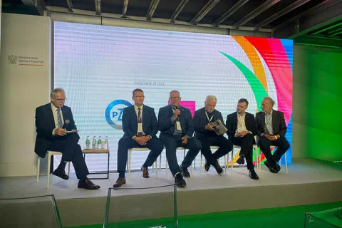 Pięciu uczestników panelu dyskusyjnego siedzących w fotelach na scenie przed kolorowym ekranem kongresu.