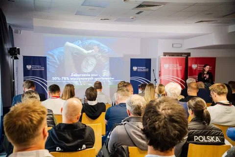 Prelegentka przy mównicy omawiająca slajd o zaburzeniach snu u wyczynowych sportowców.