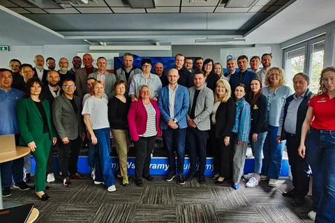 Zdjęcie grupowe uczestników drugiego dnia warsztatów stojących w sali konferencyjnej Instytutu