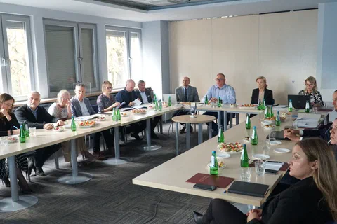 Członkowie Rady Naukowej siedzący przy stołach ustawionych w podkowę podczas posiedzenia w sali konferencyjnej
