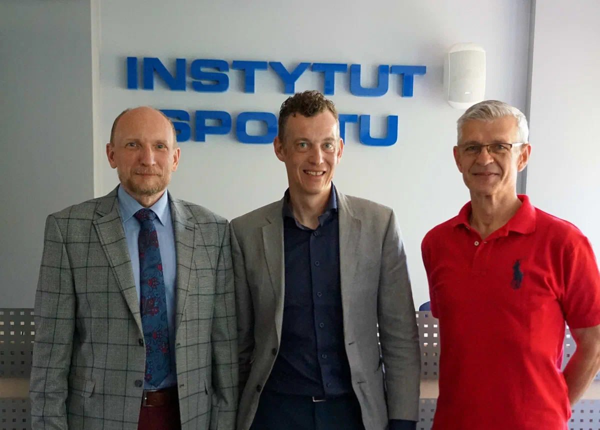Dr Raphaël Faiss (w środku) z dr. Konradem Witkiem i dr. Dariuszem Sitkowskim na tle napisu Instytut Sportu.