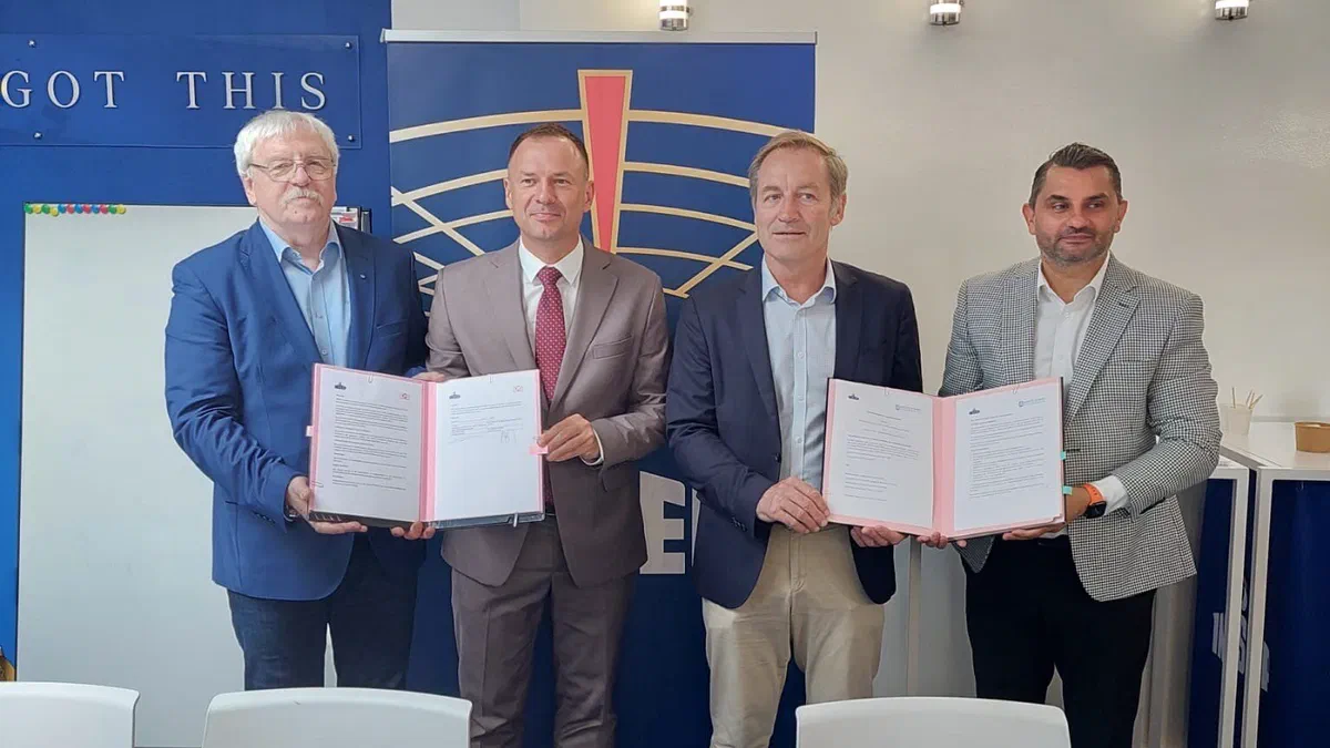 Czterech mężczyzn pozuje z otwartymi teczkami z podpisanym porozumieniem o współpracy.
