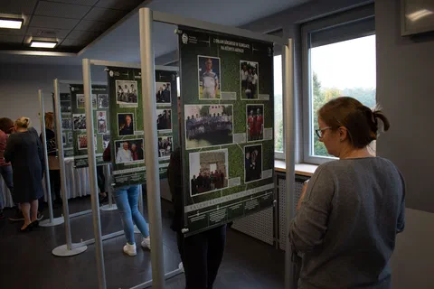 Kobieta na pierwszym planie czytająca tablicę z fotografiami z historii reprezentacji piłkarskiej