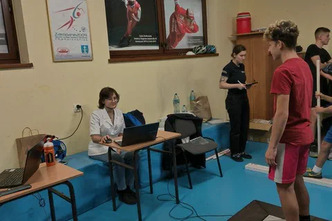 Zawodnik w czerwonej koszulce stojący na platformie dynamometrycznej w mniejszej sali pomiarowej