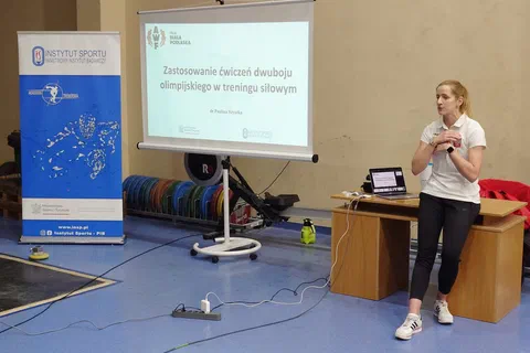 Prelegentka prowadząca wykład o zastosowaniu ćwiczeń dwuboju olimpijskiego w treningu siłowym