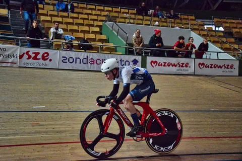 Zbliżenie na kolarza w aerodynamicznym kasku jadącego szybko na rowerze torowym