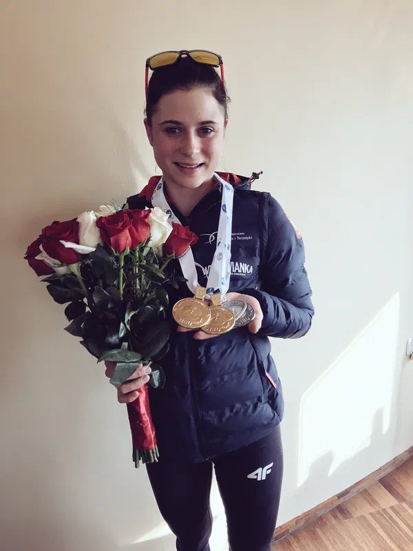 Biathlonistka Kamila Żuk z trzema medalami mistrzostw świata juniorów i bukietem róż.