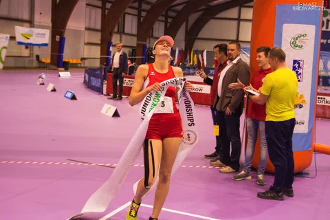 Zawodniczka w czerwonym stroju biegowym przekraczająca linię mety i zrywająca szarfę mistrzostw Europy U24 w Drzonkowie